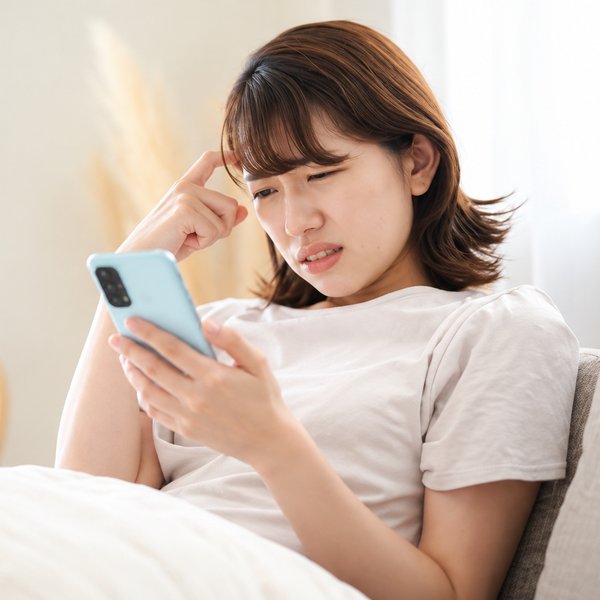 スマホを見て悩む女性