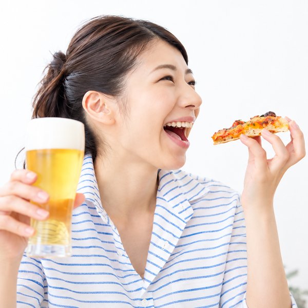 ビールとピザを楽しむ女性